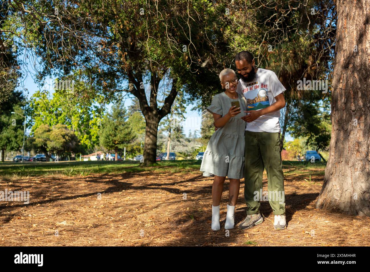 Couple using smart phone in park Stock Photo