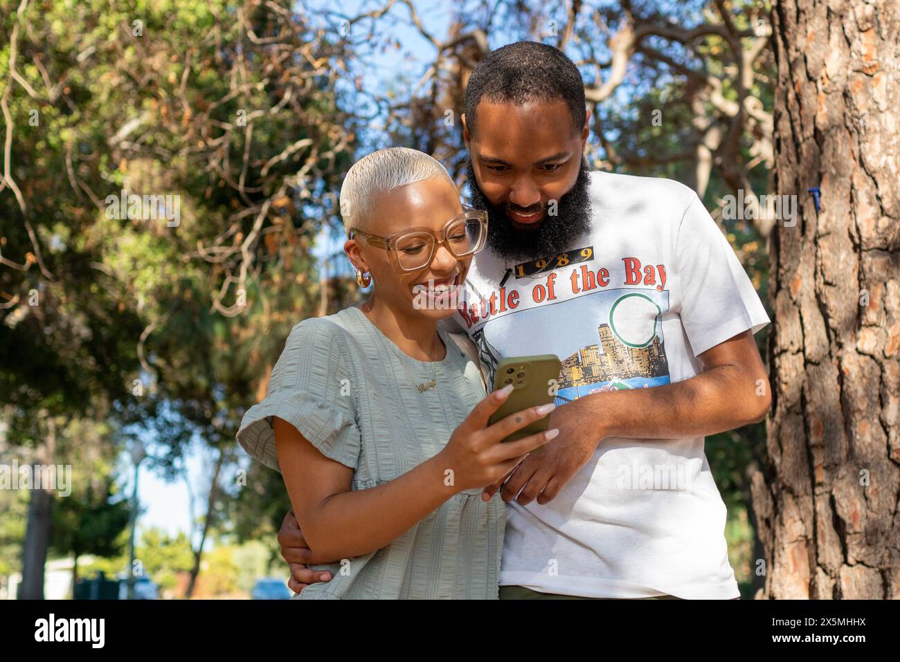 Couple using smart phone in park Stock Photo