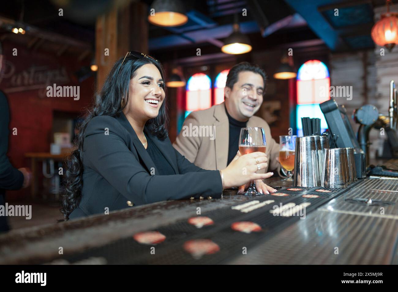 Smiling man and woman drinking alcohol in bar Stock Photo