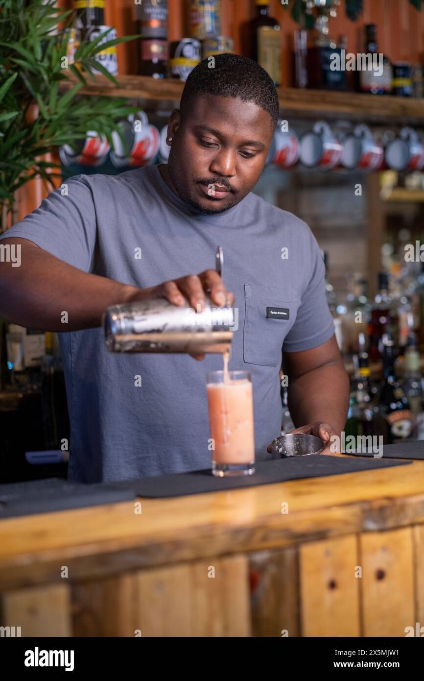 Bartender pouring cocktail into glass Stock Photo