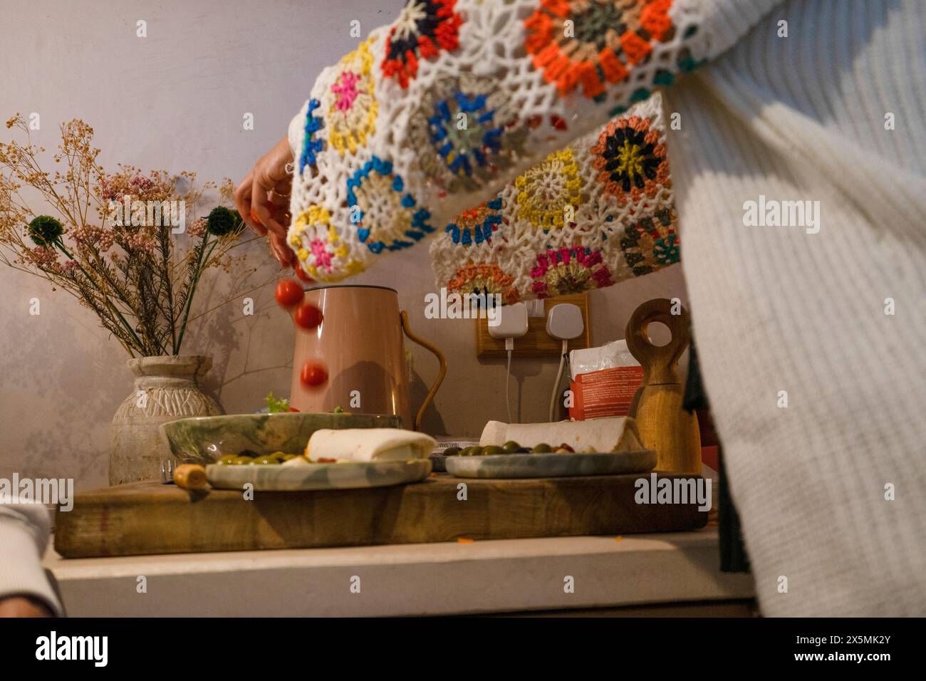 Close-up of woman adding cherry tomatoes to salad?in kitchen Stock Photo