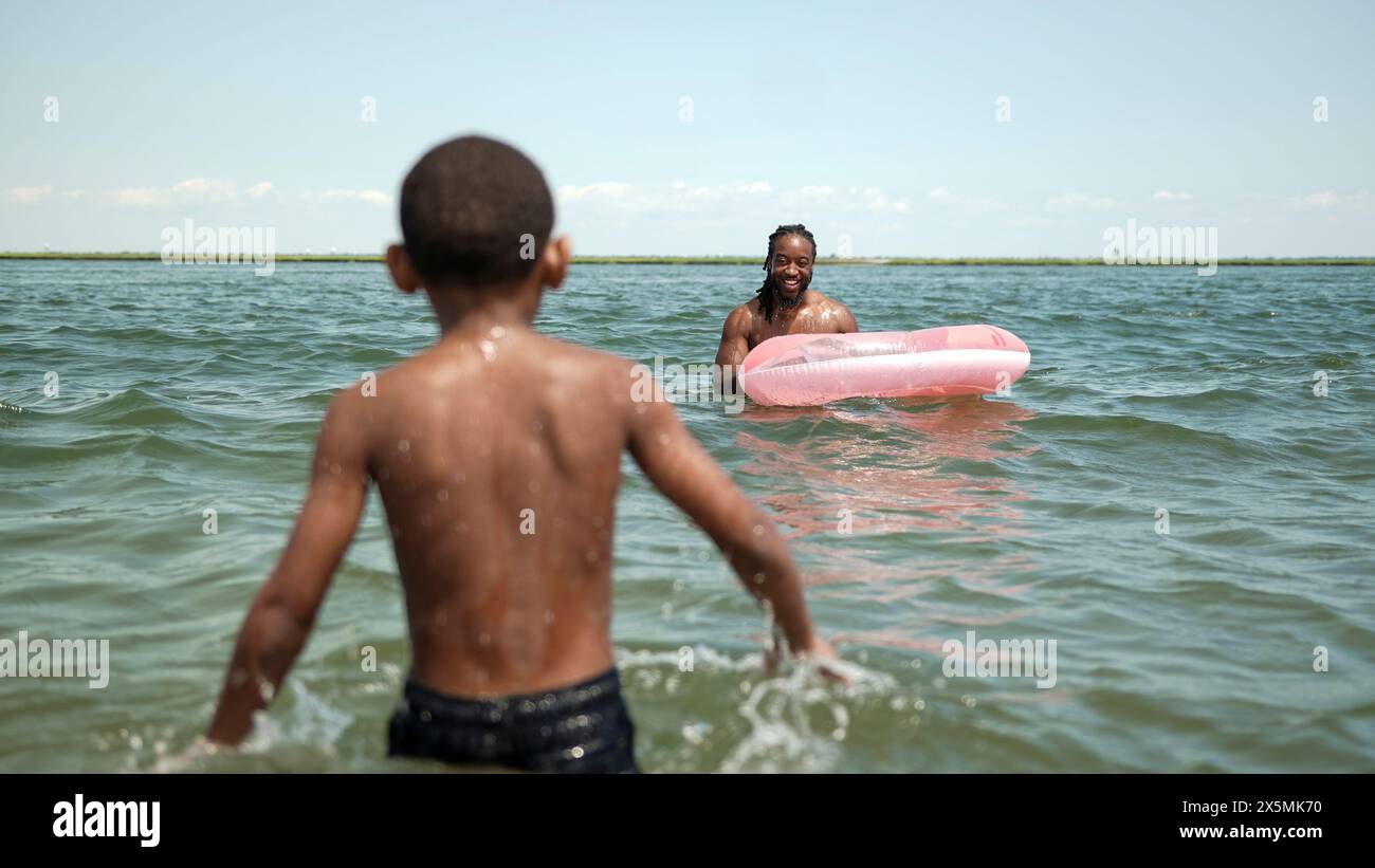 USA, Father and son playing with inflatable ring in sea Stock Photo