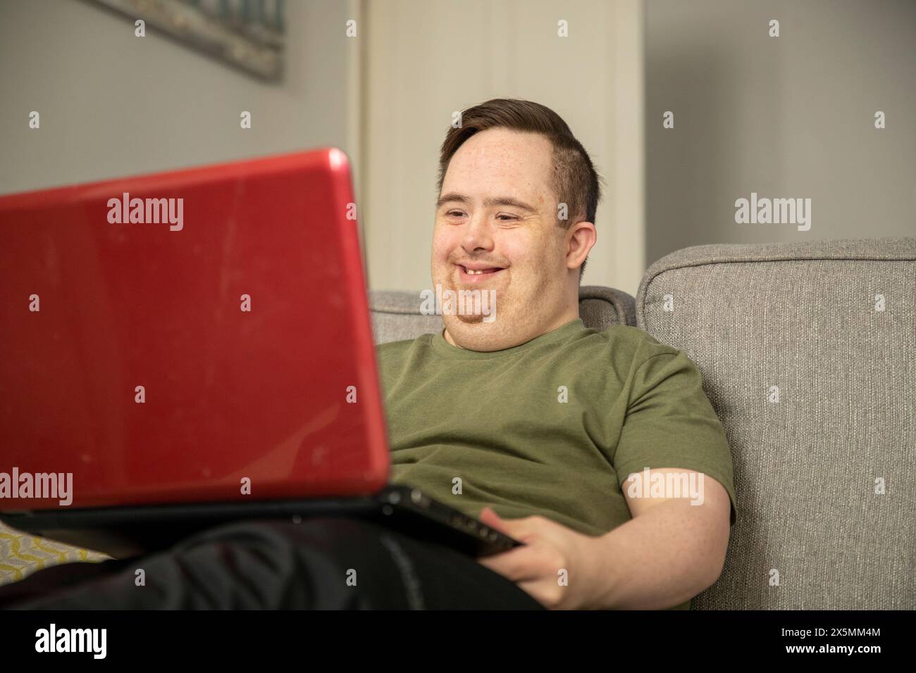 Man sitting on sofa and using laptop Stock Photo