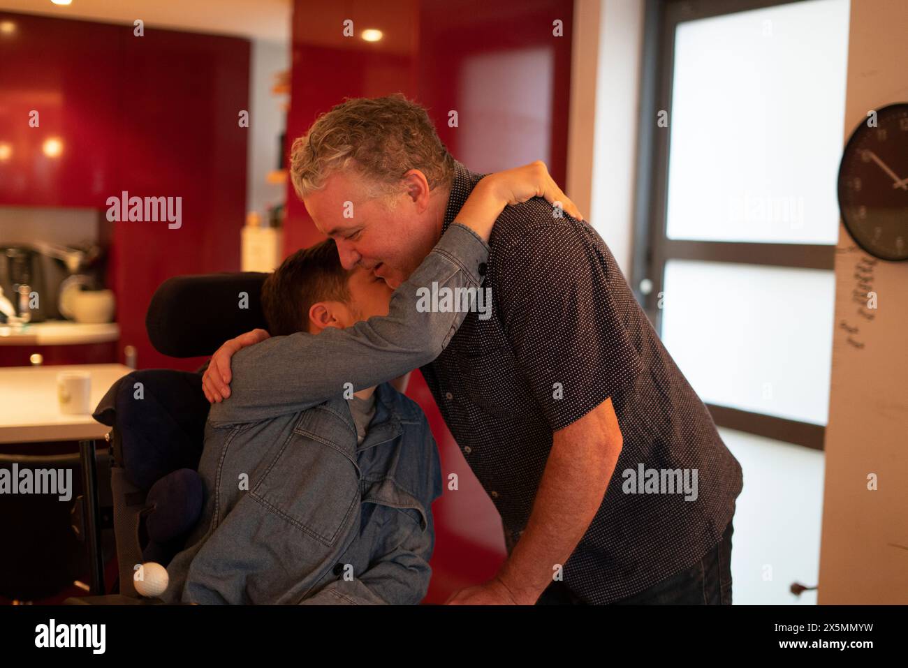 Father embracing disabled son at home Stock Photo