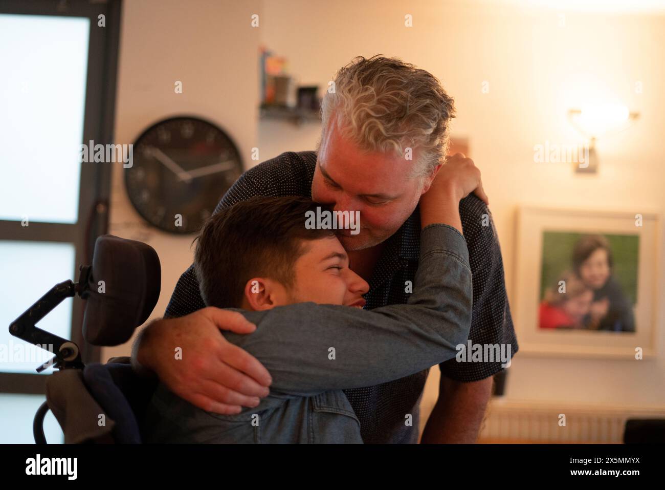 Father embracing disabled son at home Stock Photo