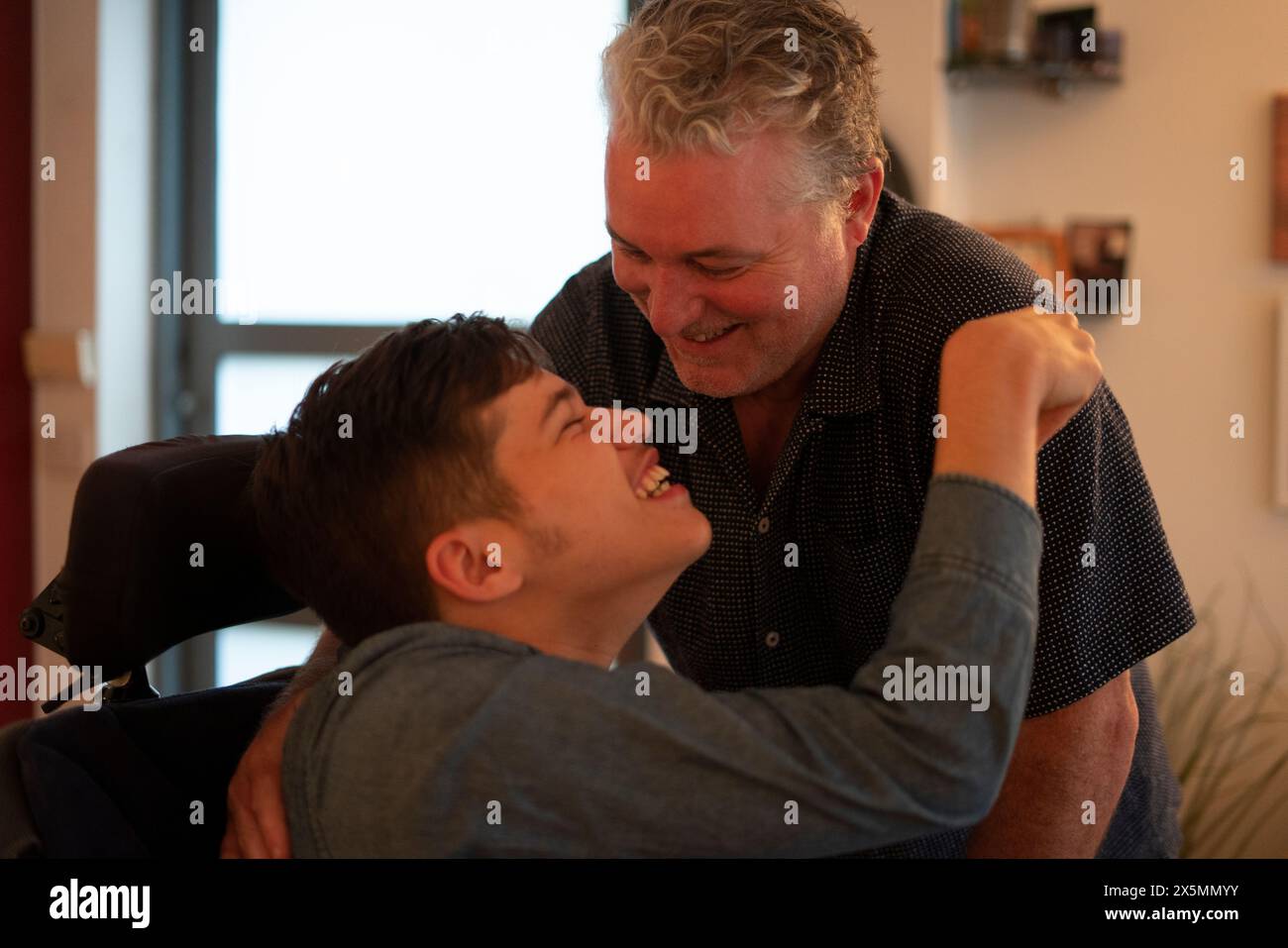 Father embracing disabled son at home Stock Photo