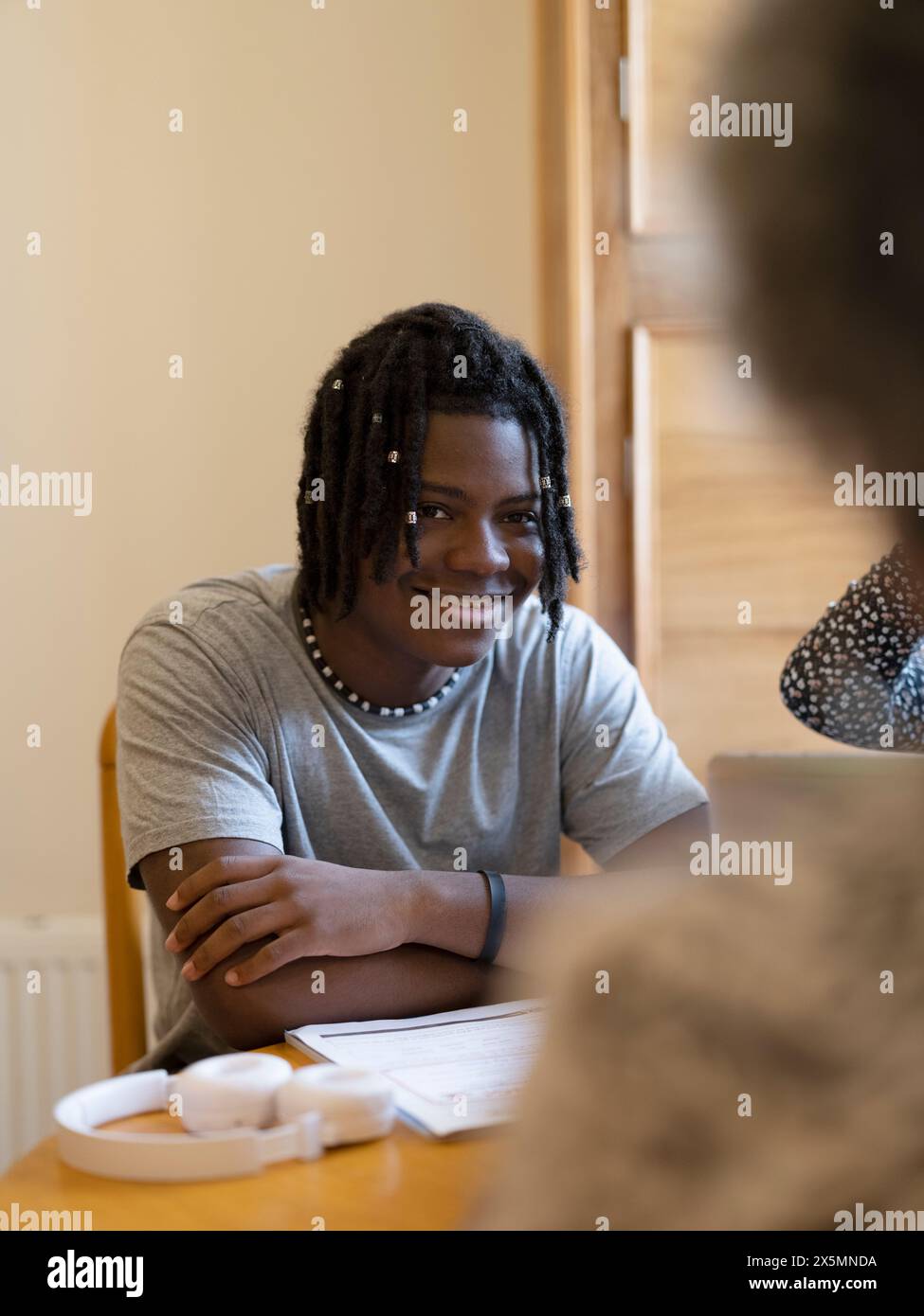 Smiling teenage boy sitting at table at home Stock Photo