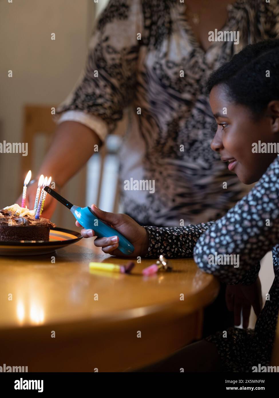 Mother And Daughter Lighting Candles On Birthday Cake Stock Photo Alamy