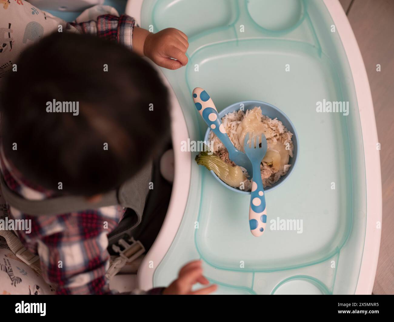 Baby boy eating dinner in high chair Stock Photo