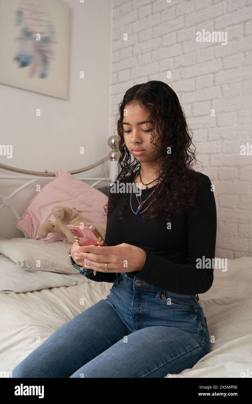 Teenage girl using smart phone on bed at home Stock Photo - Alamy