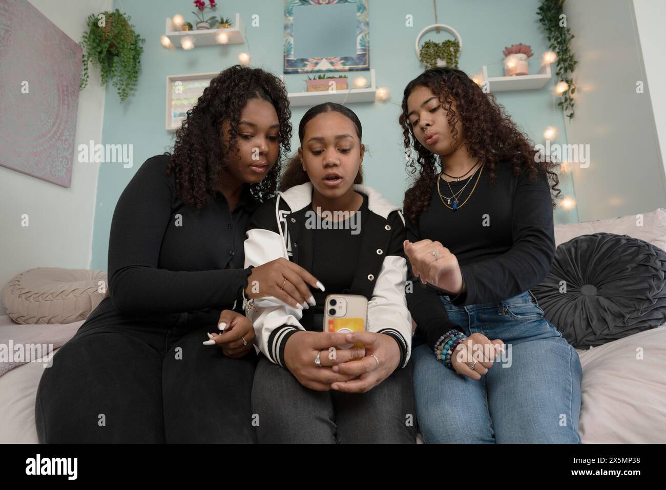Teenage girls using smart phone while sitting on bed Stock Photo - Alamy