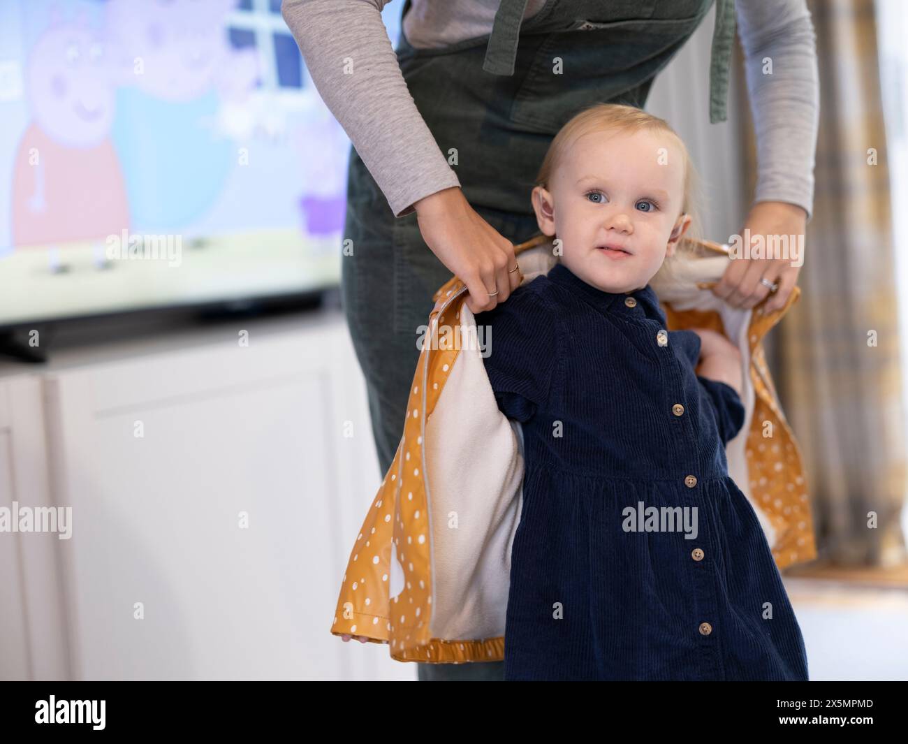 Mother Helping Daughter To Put On Raincoat Stock Photo Alamy