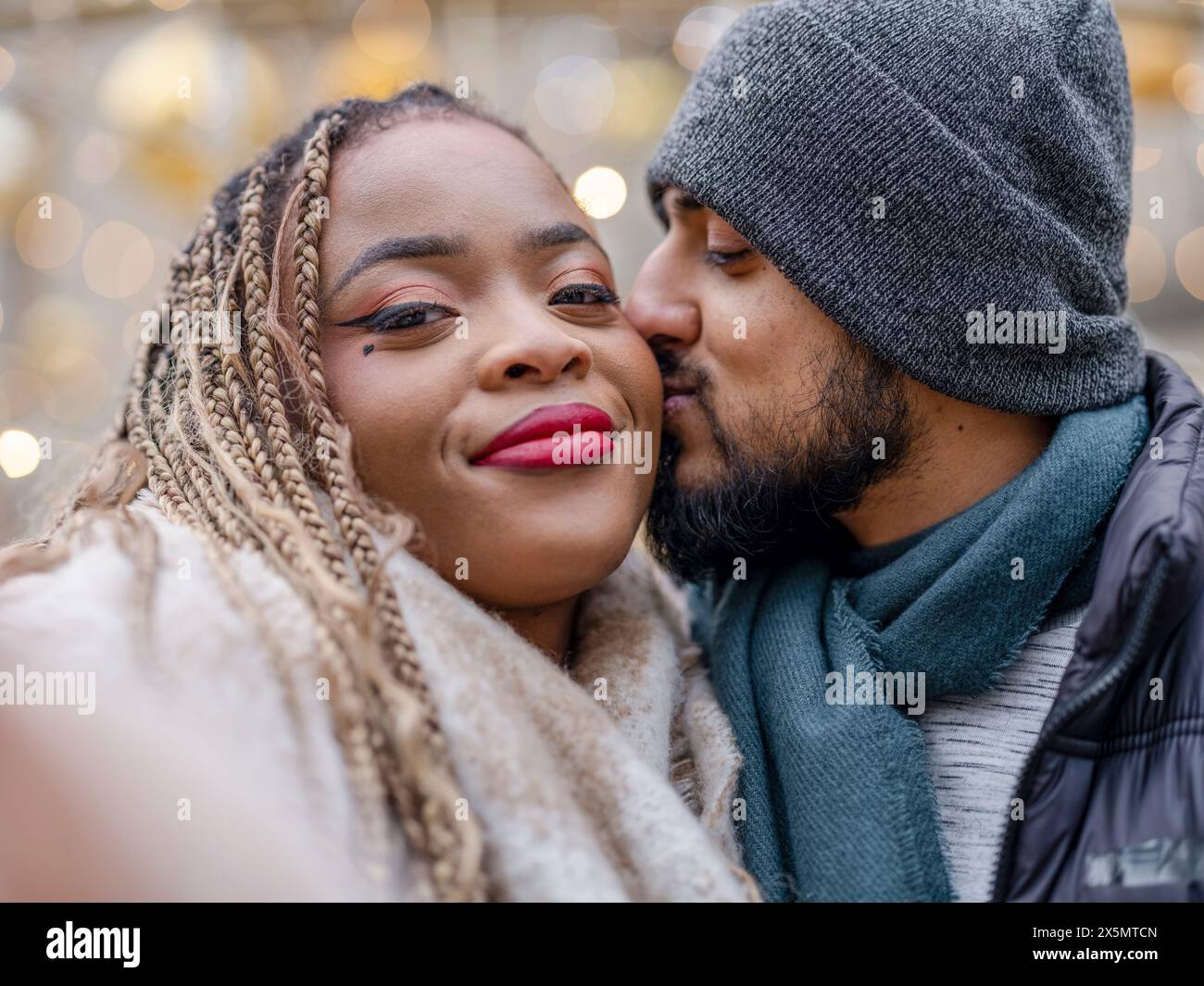 Man kissing girlfriend on cheek Stock Photo - Alamy