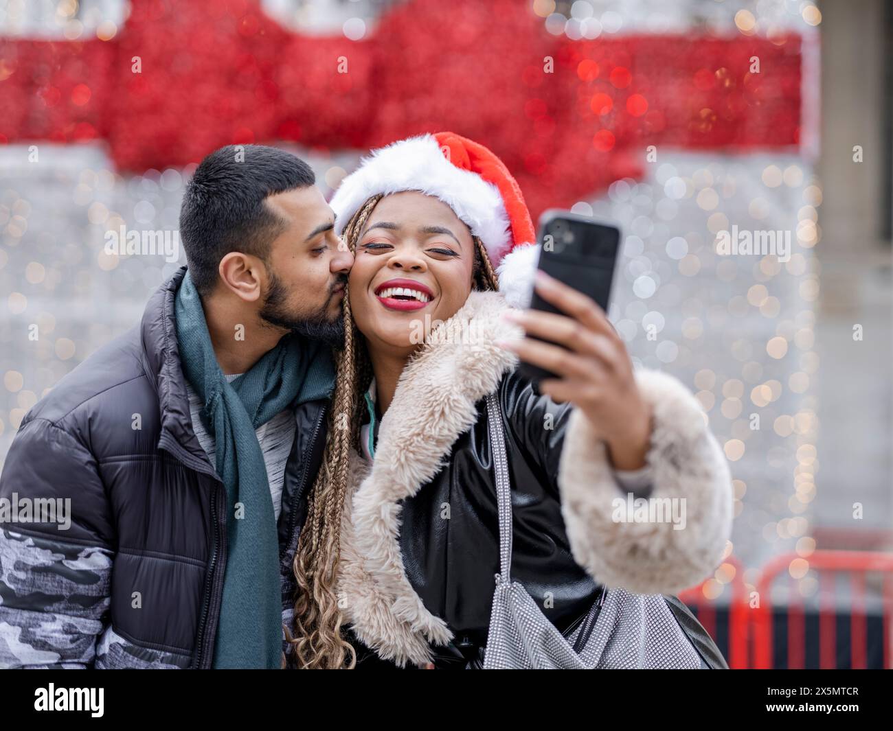 Young couple taking selfies against Christmas decorations Stock Photo