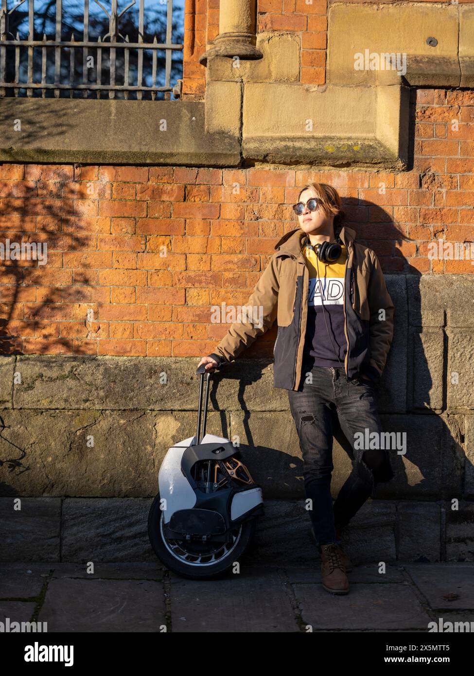 Portrait of man with electric unicycle against brick wall Stock Photo