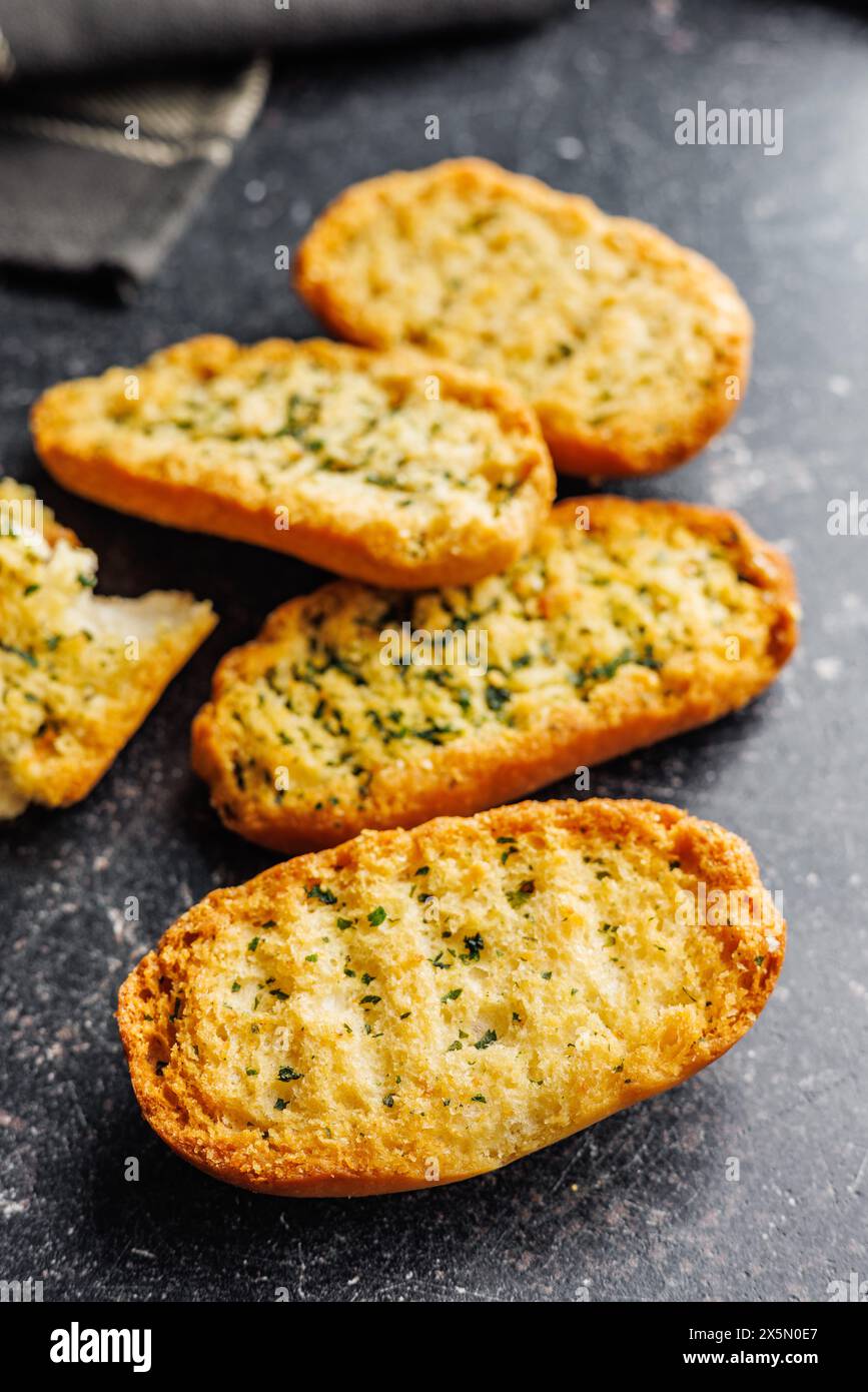 Garlic crisp bread Slices Topped With Herbs on a black table. Stock Photo