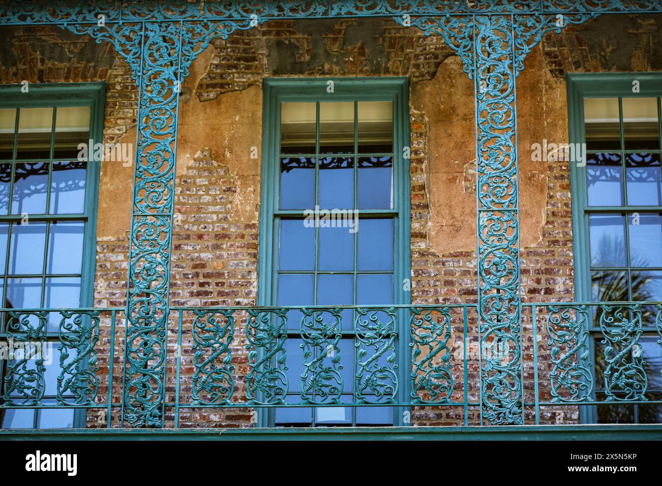 Charleston, South Carolina, USA. Green ornate wrought iron balcony, windows and old brick building. (Editorial Use Only) Stock Photo