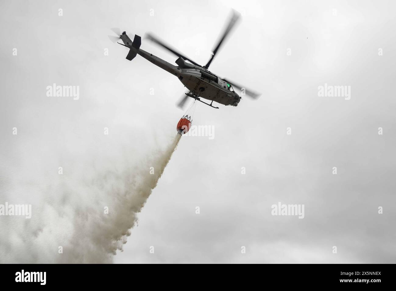 May 1, 2024 - Camp Pendleton, California, USA - A U.S. Marine Corps UH-1Y Venom, assigned to Marine Light Attack Helicopter Squadron 169, Marine Aircraft Group 39, 3rd Marine Aircraft Wing, drops water from a Bambi firefighting bucket over a target area during the annual Cory Iverson Wildland Firefighting exercise at the Las Pulgas Lake at Marine Corps Base Camp Pendleton, California, May 1, 2024. The Cory Iverson Wildland Firefighting exercise is an annual event focusing on interagency cooperation between the California Department of Forestry and Fire Protection, San Diego County Sheriff's De Stock Photo