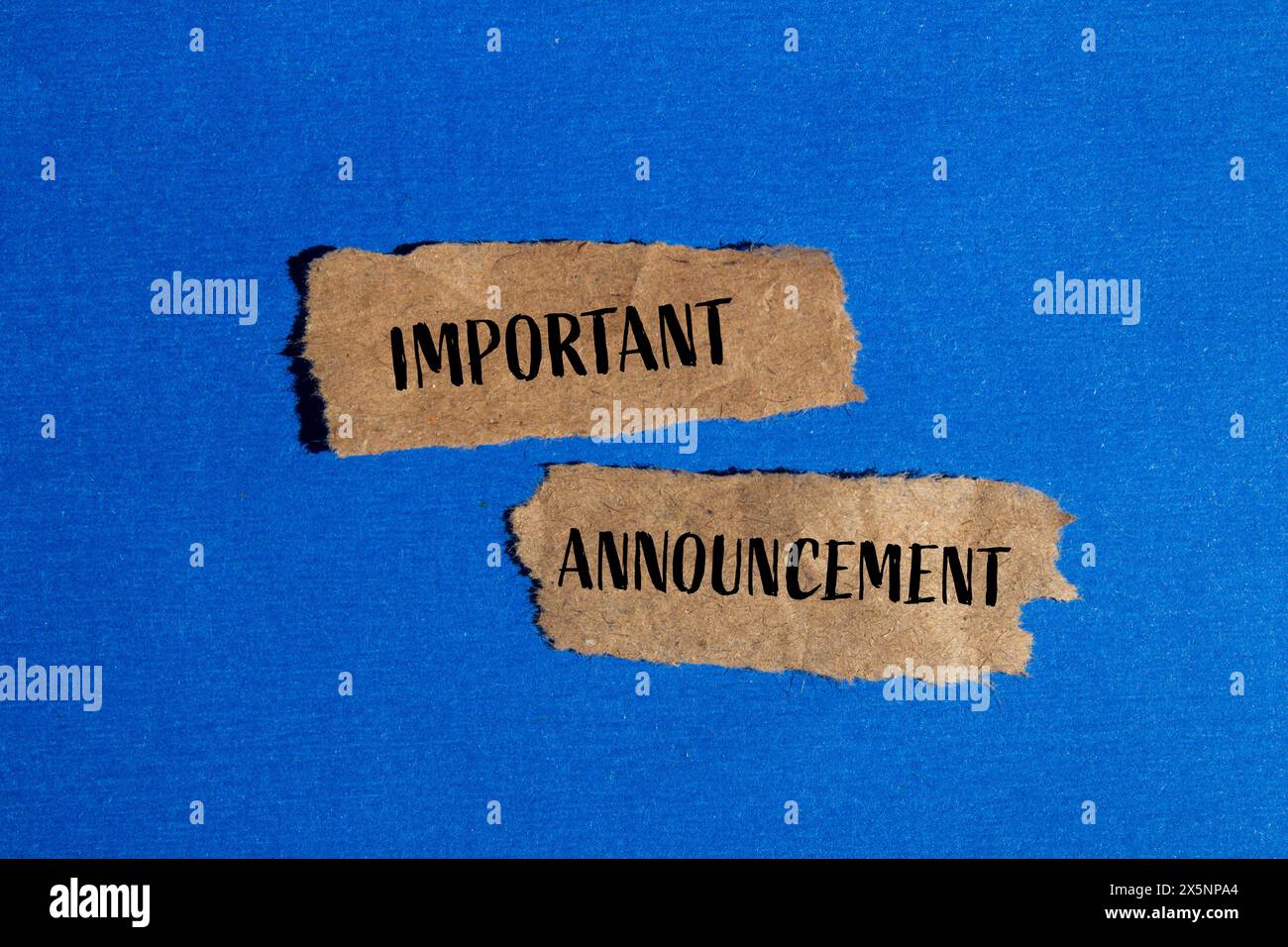 Important announcement words written on torn brown paper pieces with blue background. Conceptual important announcement symbol. Copy space. Stock Photo