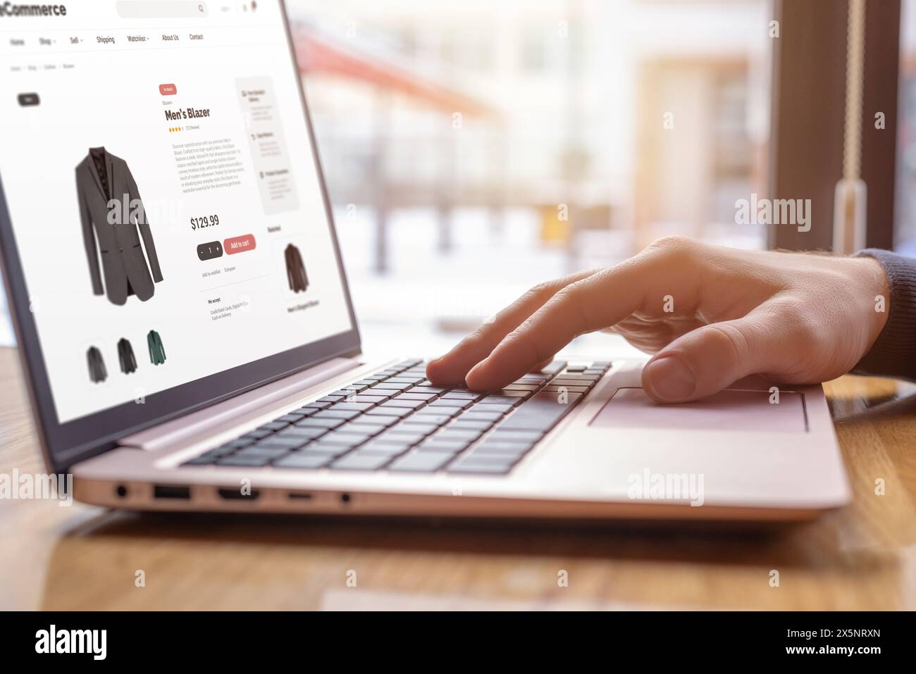 Close-up of hands typing on laptop, shopping online for men's blazer. Modern digital shopping experience for fashion enthusiasts Stock Photo