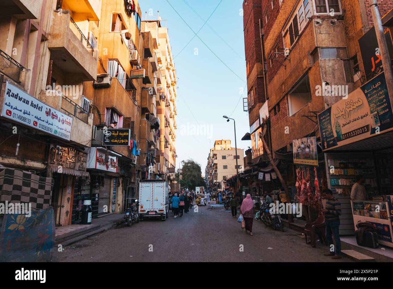 a bustling street with various stalls selling food and clothing in the city of Aswan, Egypt Stock Photo