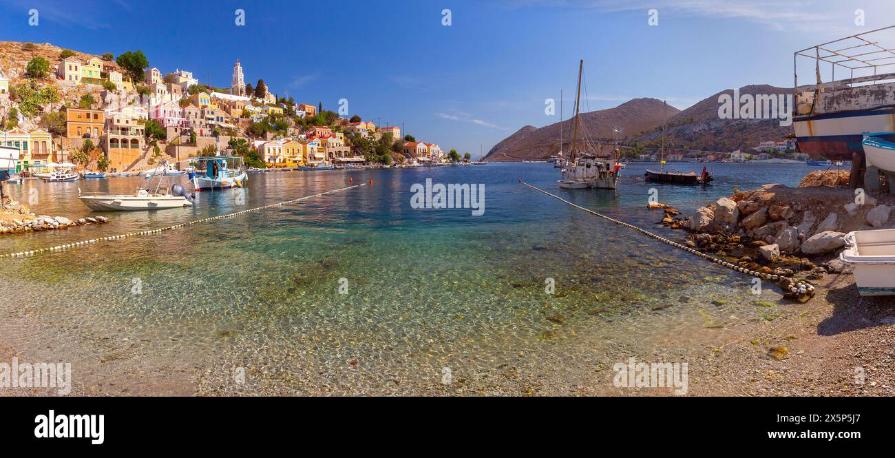 Hillside panoramic view of the colorful buildings and busy harbor on Symi Island, Greece. Stock Photo