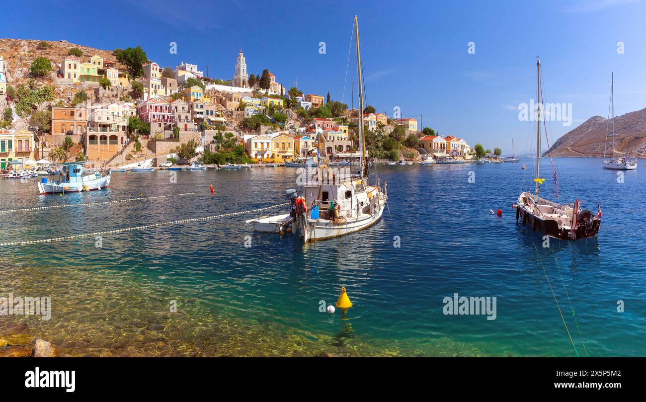 Hillside view of the colorful buildings and busy harbor on Symi Island, Greece. Stock Photo