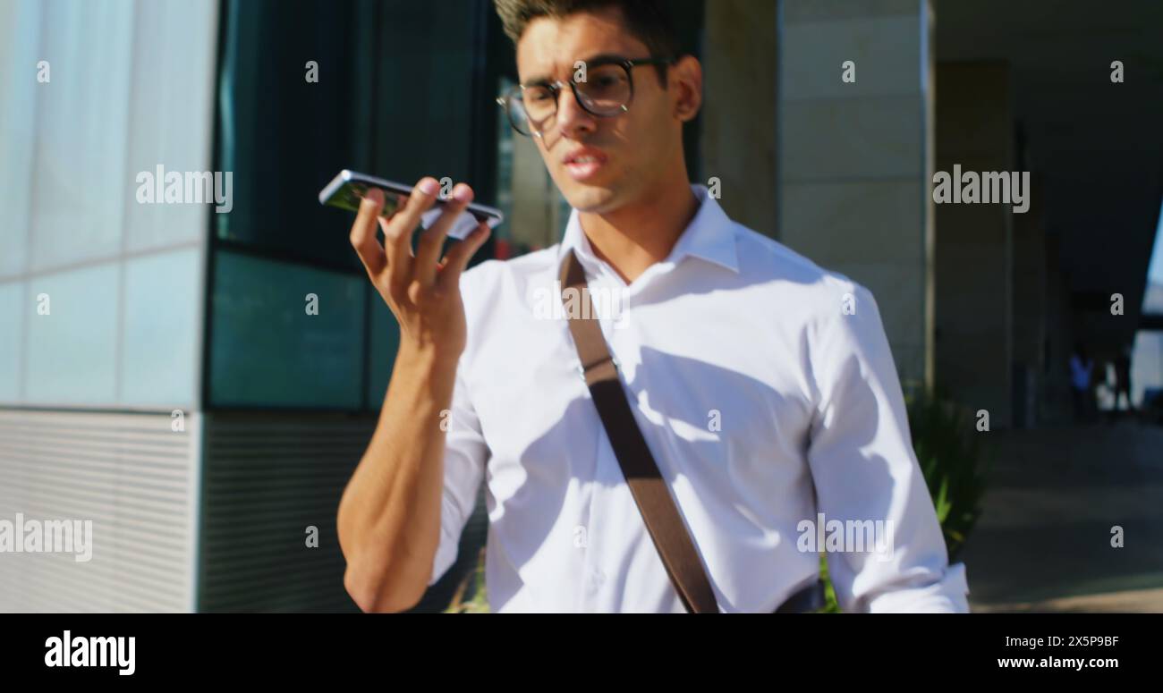 Young biracial man wearing glasses, talking on smartphone outside Stock Photo