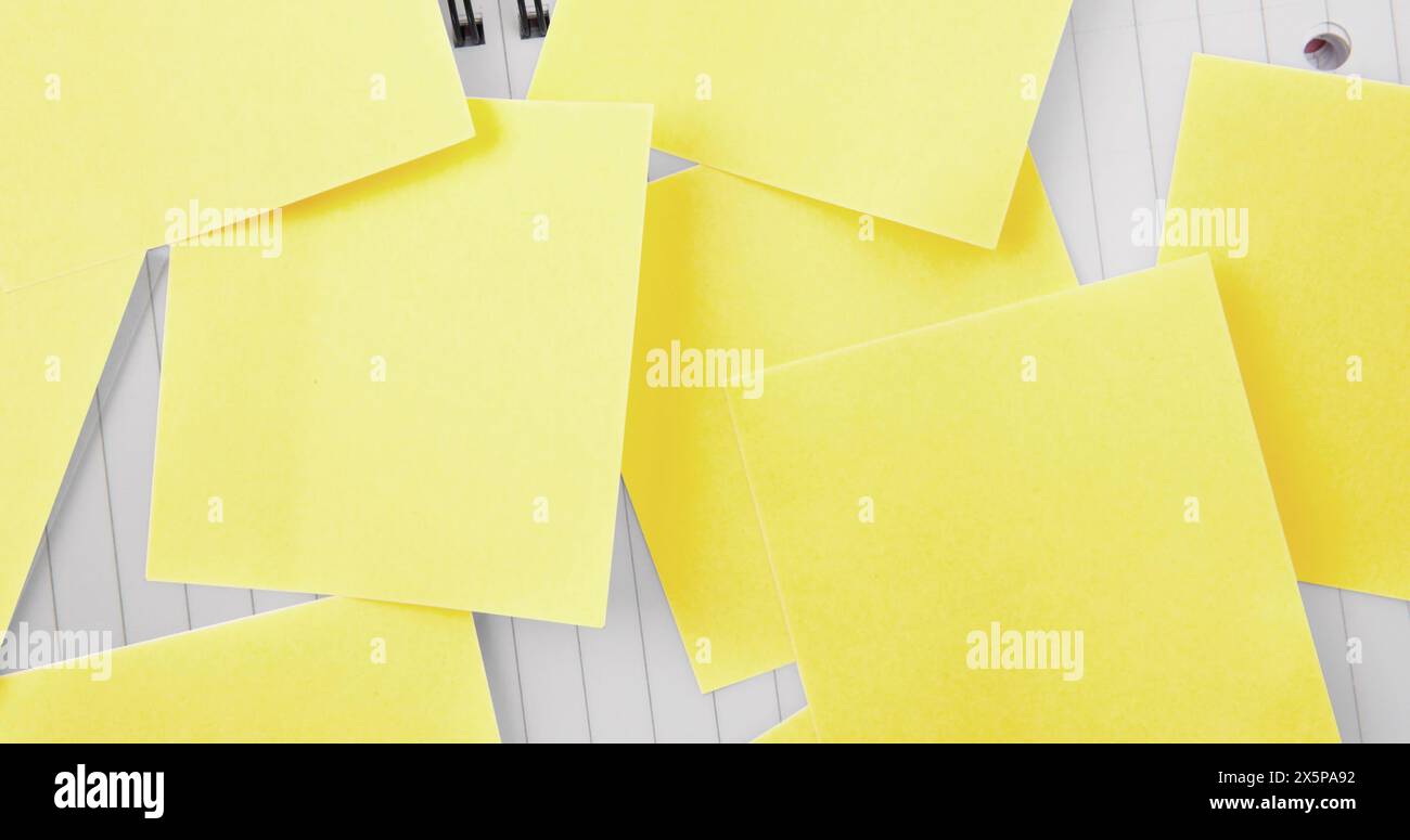 Multiple yellow sticky notes lying on white wooden surface Stock Photo