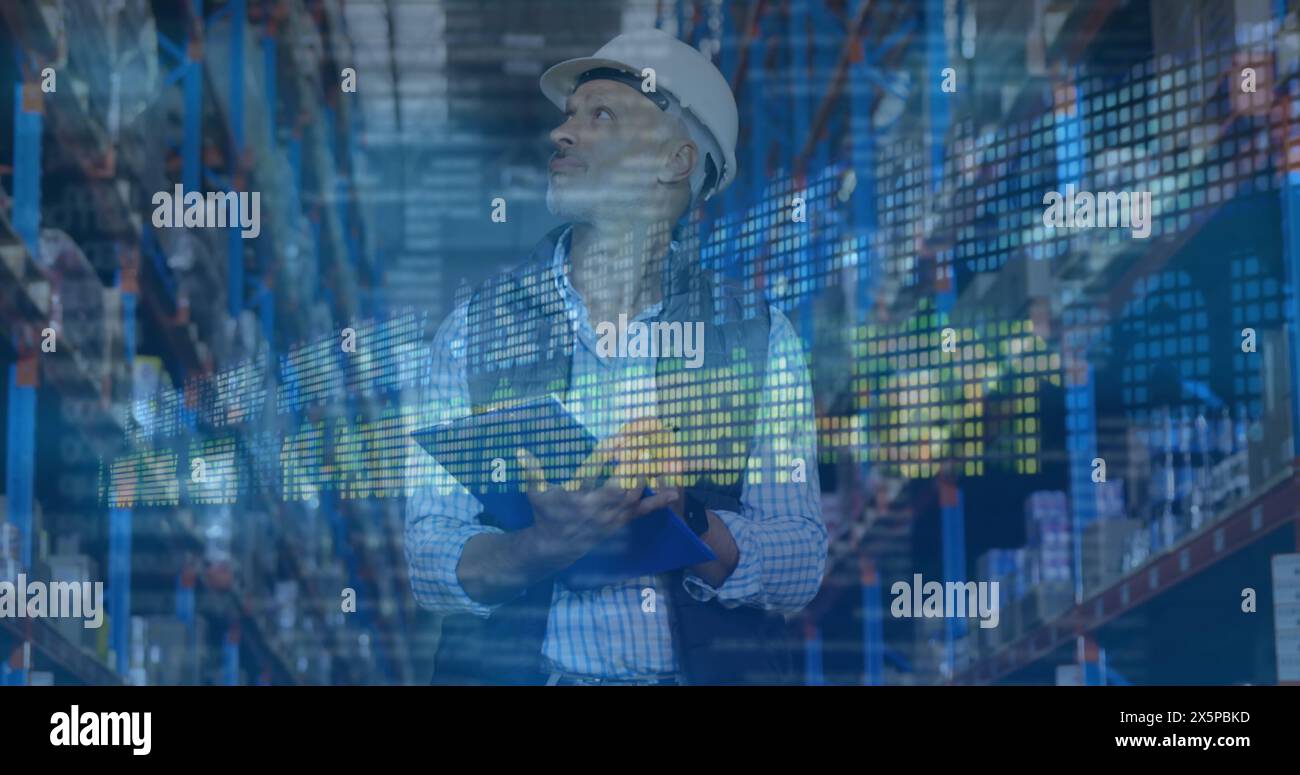 Caucasian middle-aged man wearing hard hat, holding clipboard in warehouse Stock Photo