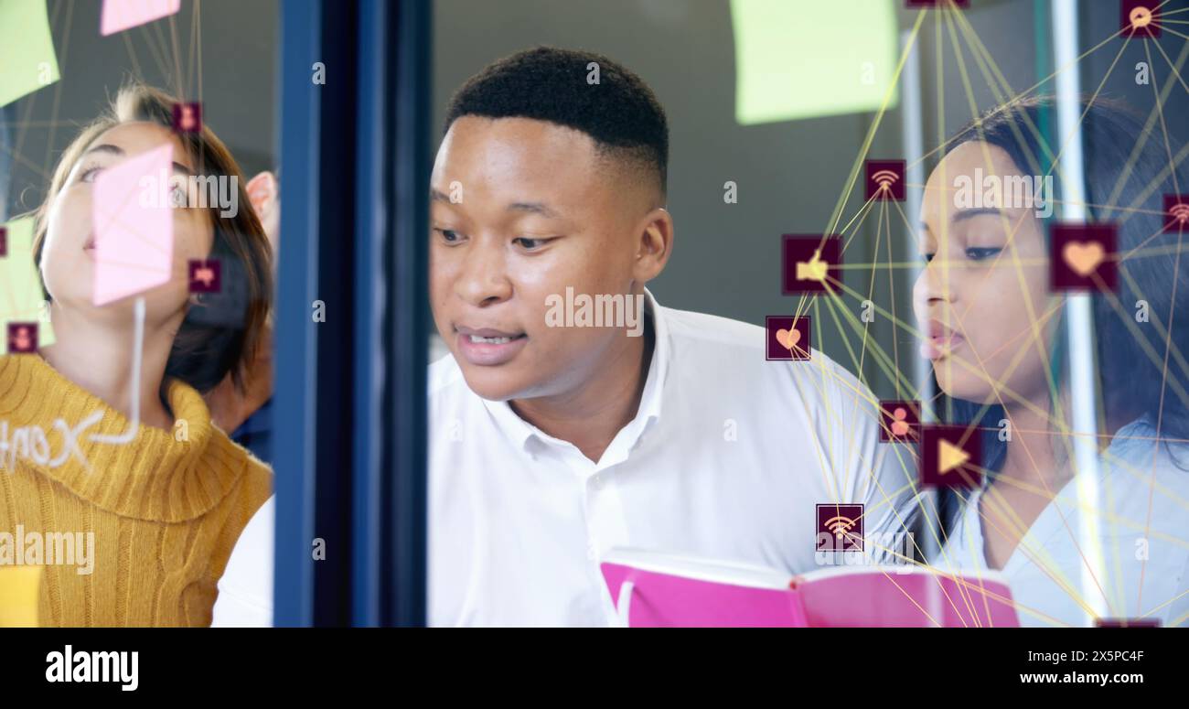 Image of two globes of digital icons over diverse office colleagues discussing over memo notes Stock Photo