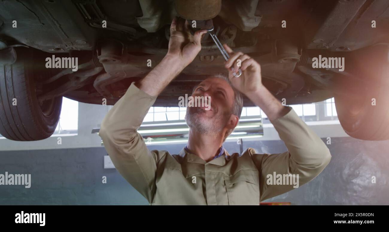 Caucasian mechanic working under car, holding a wrench Stock Photo