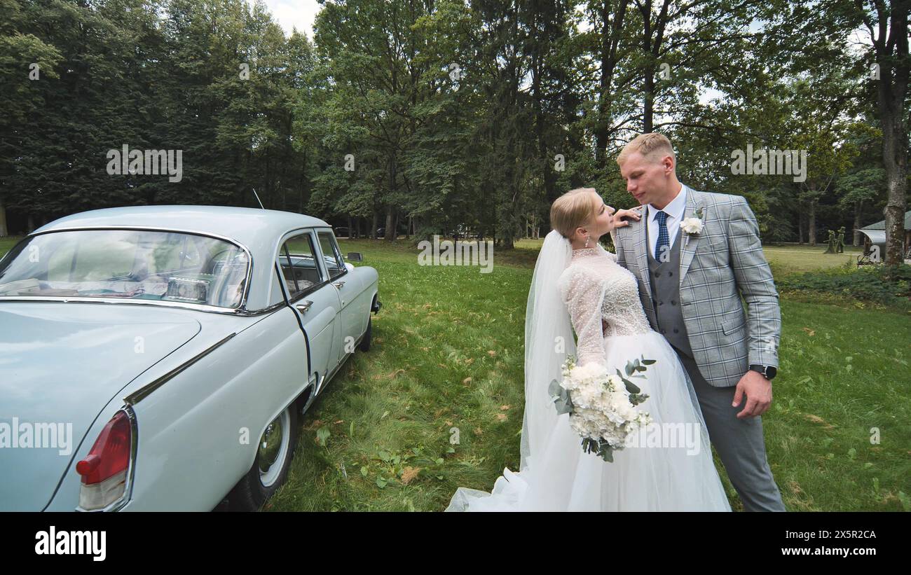 Bride and groom posing in front of white car for wedding picture Stock ...