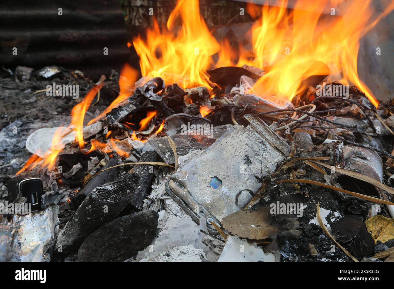 Philippines E waste pollution problem: Electronic  burned among household trash: iPhone, power bank lithium battery, cables, charger, technologic dump Stock Photo