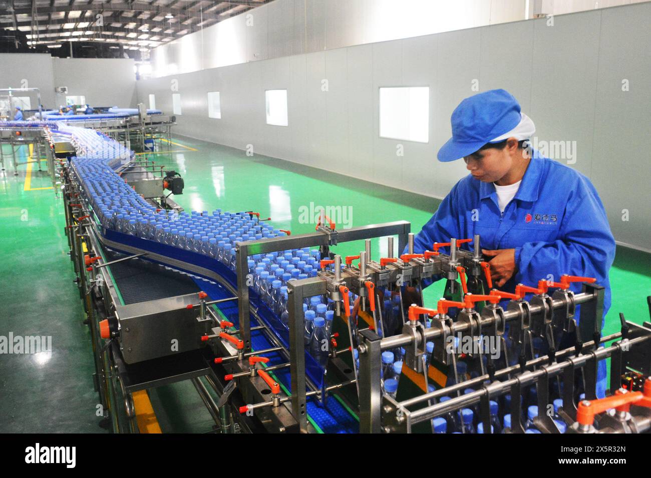 ANQING, CHINA - MAY 11, 2024 - A worker is working on a bottled water production line at a workshop of a beverage company in Anqing city, East China's Stock Photo