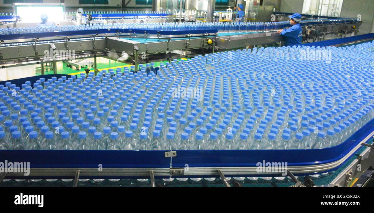 ANQING, CHINA - MAY 11, 2024 - A worker is working on a bottled water production line at a workshop of a beverage company in Anqing city, East China's Stock Photo