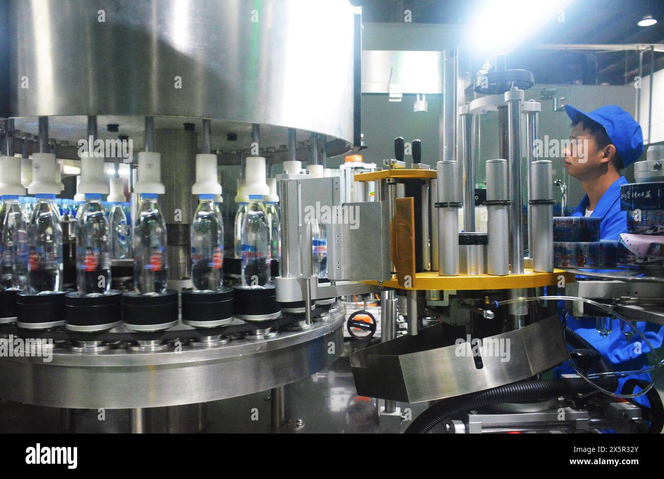 ANQING, CHINA - MAY 11, 2024 - A worker is working on a bottled water production line at a workshop of a beverage company in Anqing city, East China's Stock Photo