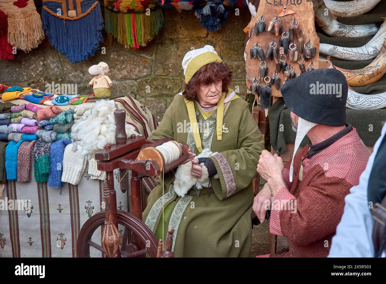 Baiona, Pontevedra, Galicia, Spain; March, 04,2023; An artisan spinner with a spinning wheel looks towards another artisan at the medieval festival of Stock Photo