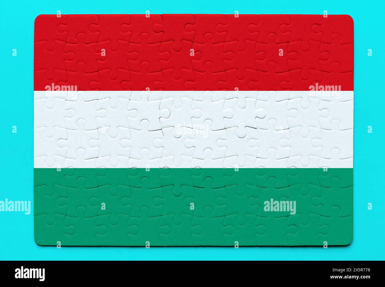 Creative rendition of the Hungarian flag crafted from jigsaw puzzle pieces, set against a calming blue backdrop. Culture, national identity and teamwo Stock Photo