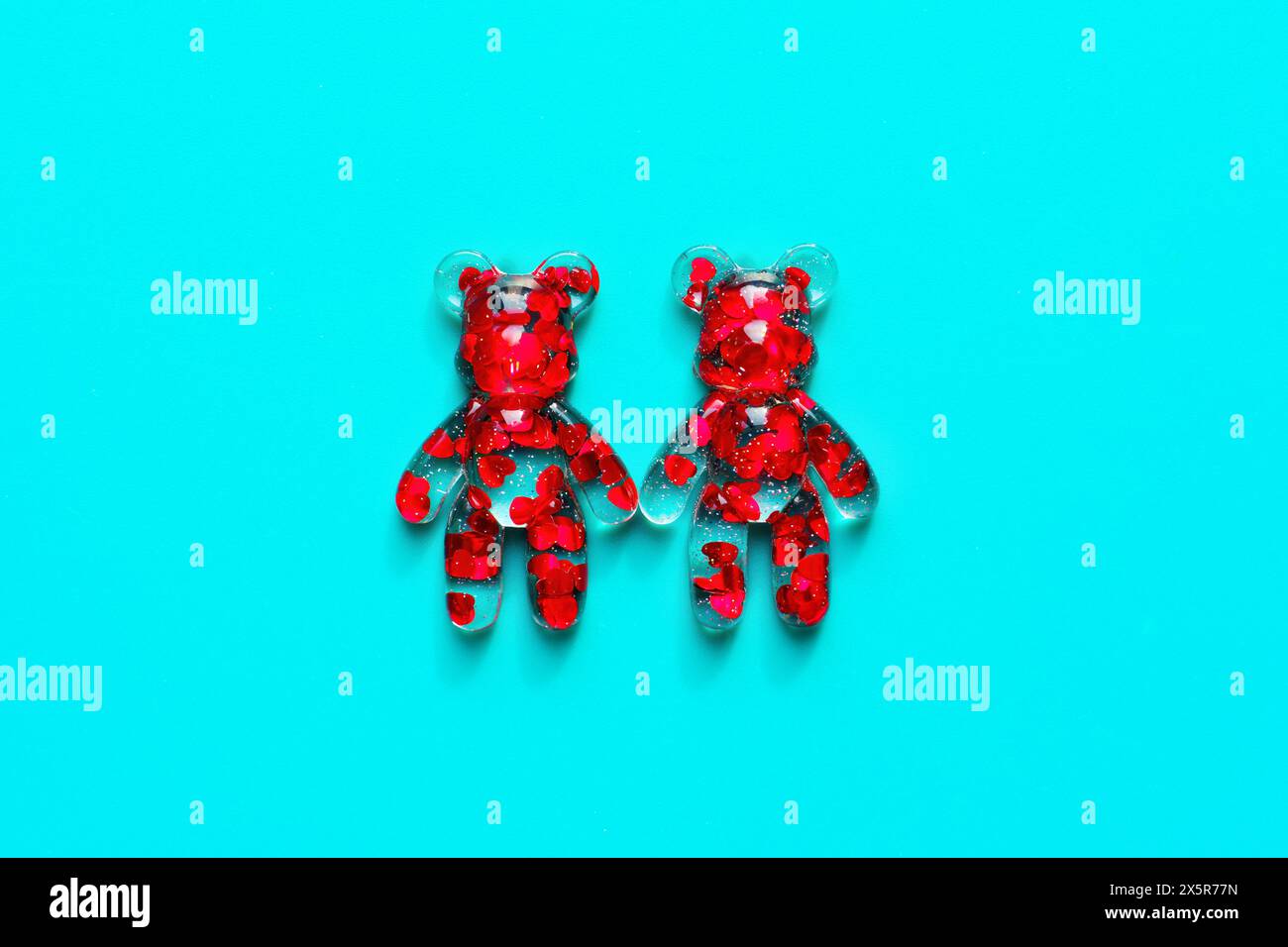 Pair of transparent bear figurines adorned with floating red hearts inside. Valentine's Day related concept. Stock Photo