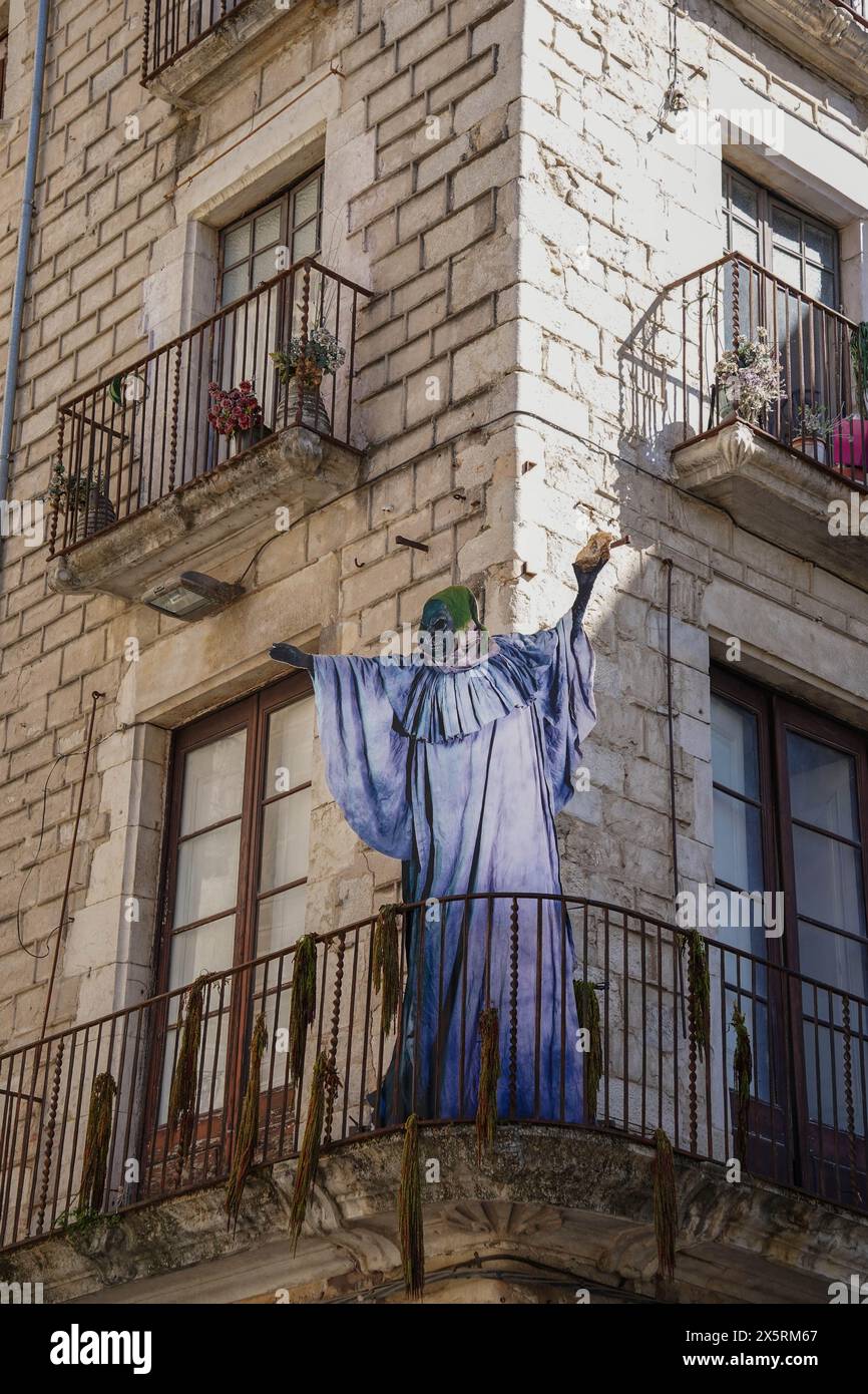 A giant of a witch in a blue robe is on a balcony. Girona in Temps de