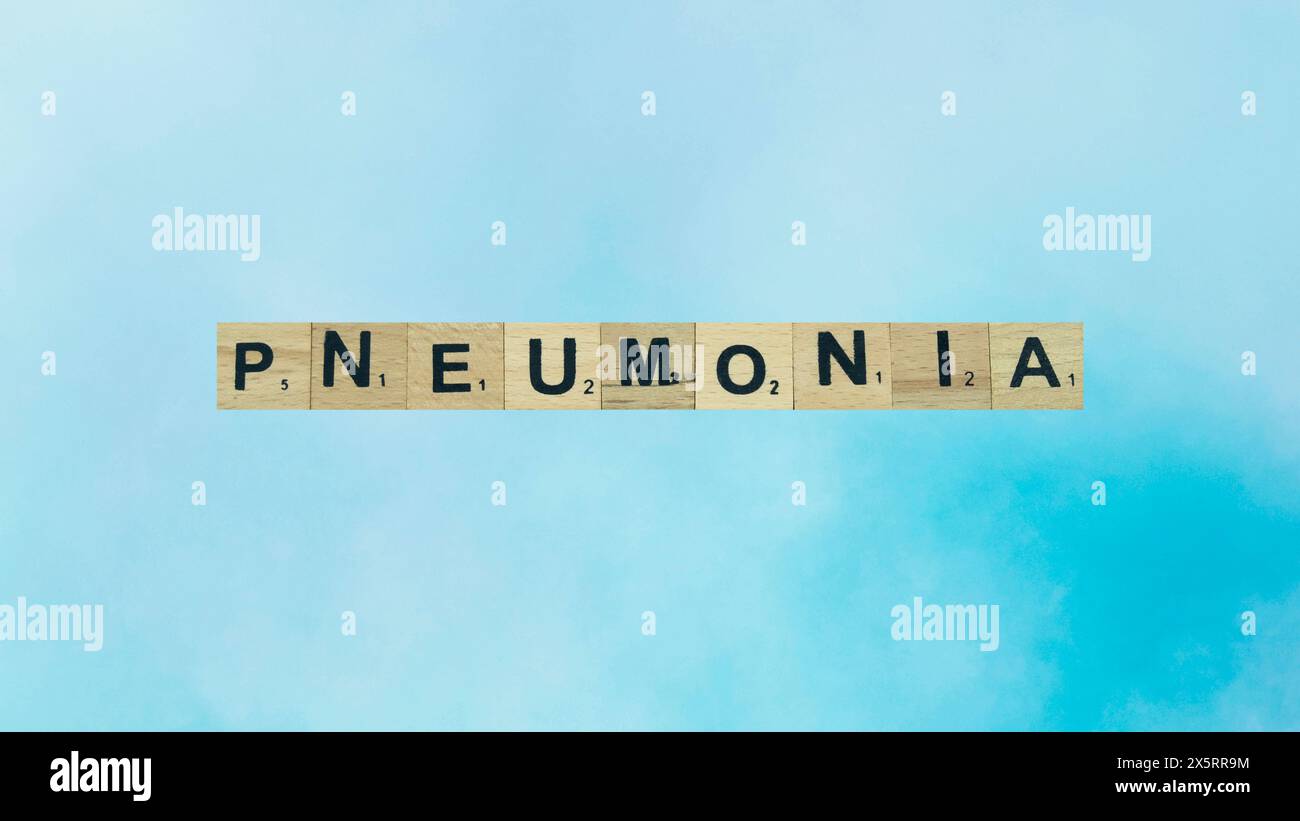 Pneumonia word written on wood block. pneumonia text on blue blur background for your desing, coronavirus concept top view. Stock Photo