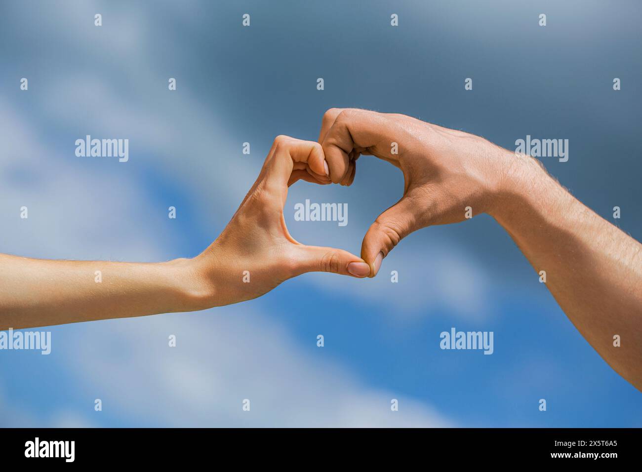 Girl and man hands in heart form over blue sky background. Love ...