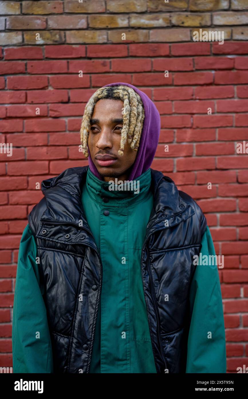 Young man standing against brick wall Stock Photo