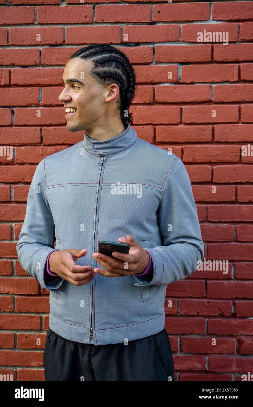 Smiling young man using phone outdoors Stock Photo