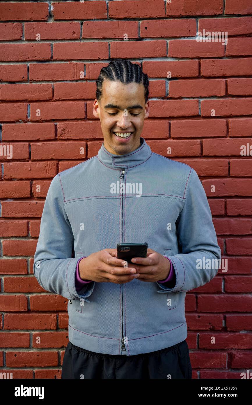 Smiling young man using phone outdoors Stock Photo
