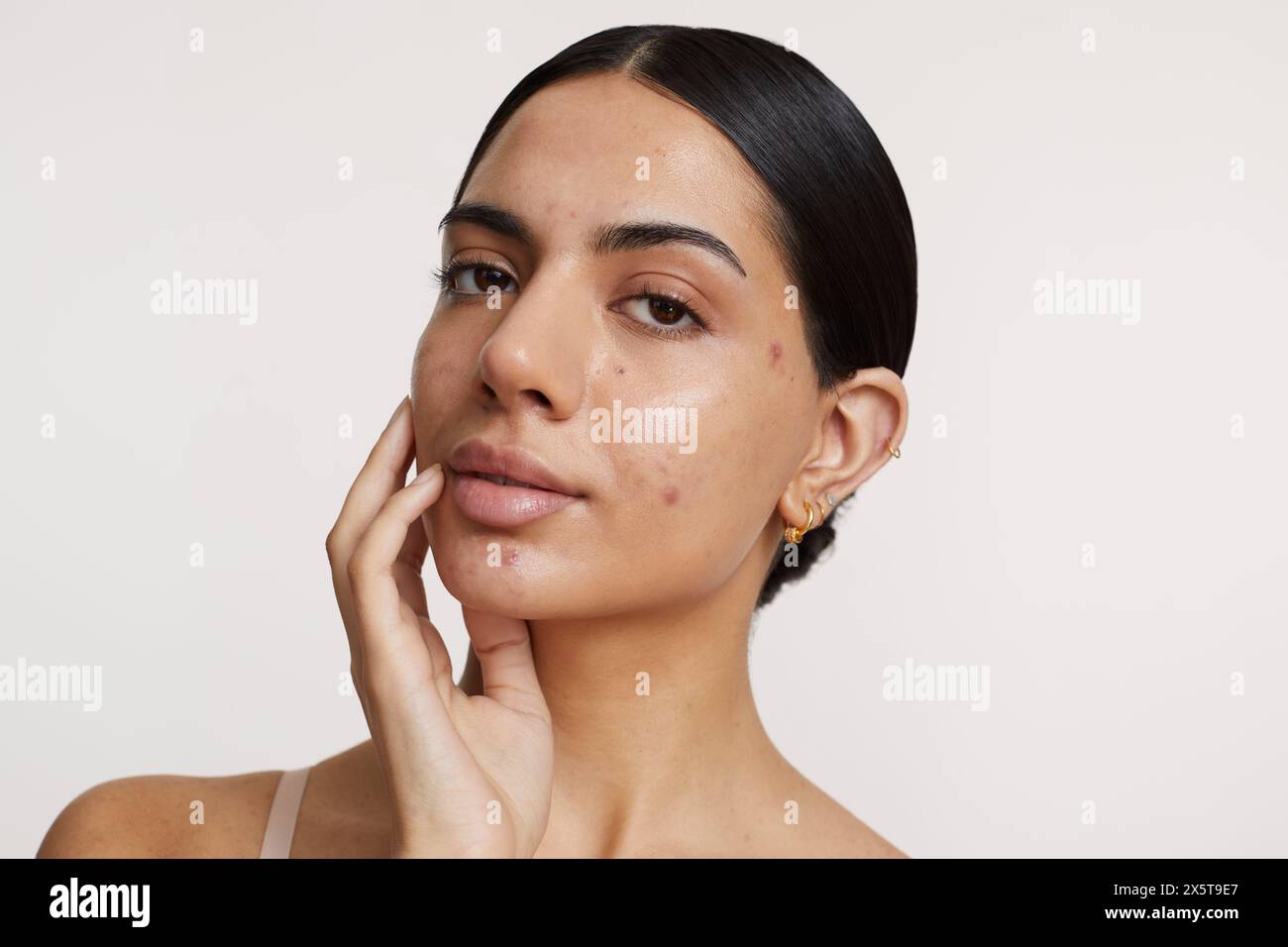 Portrait of young woman looking at camera against white background Stock Photo