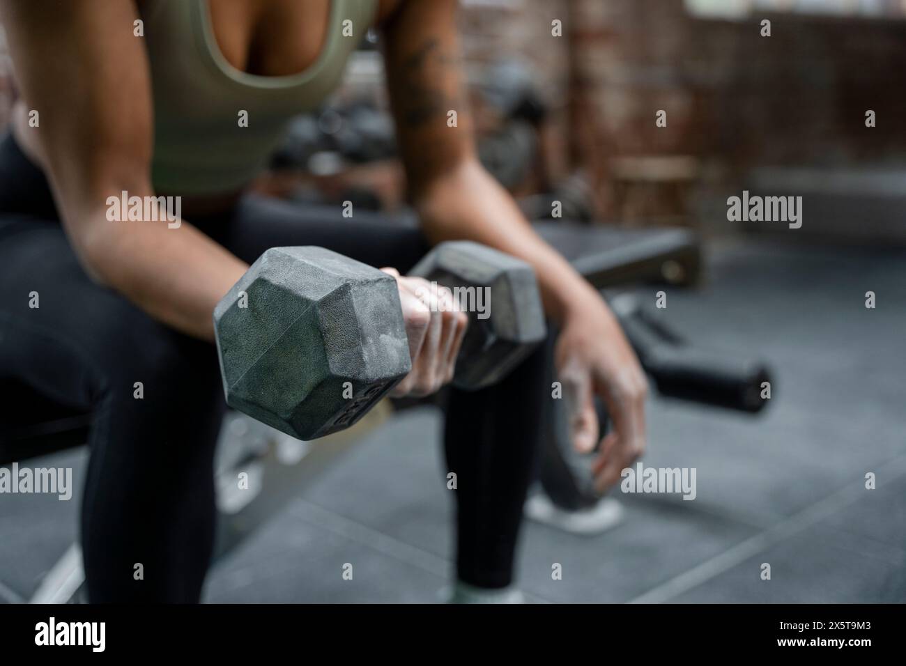 Woman holding dumbbell during weight training on gym Stock Photo
