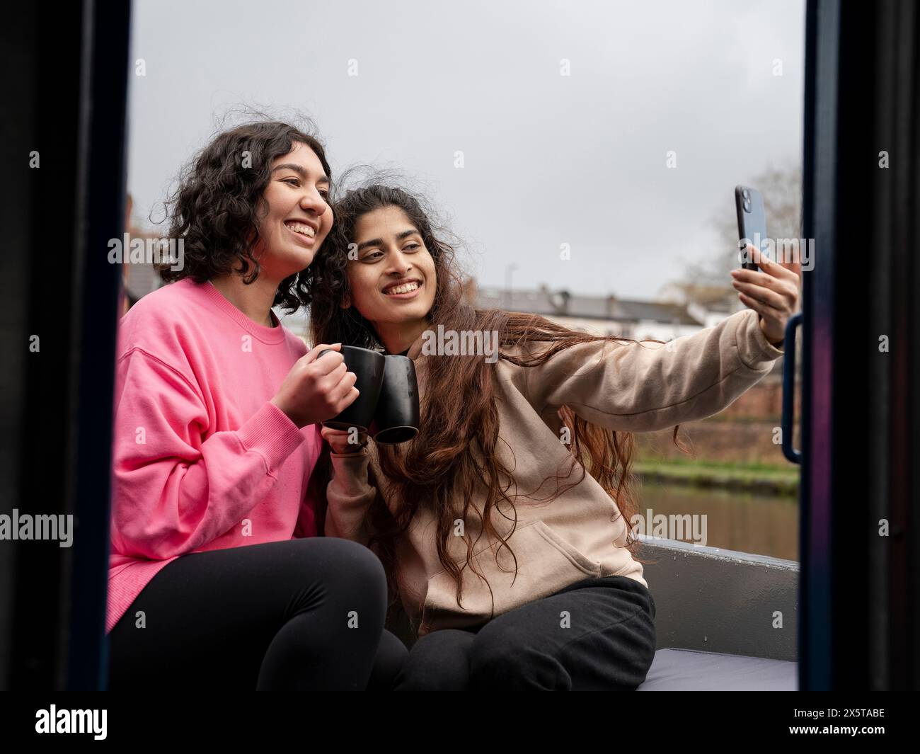 Two smiling women sitting on boat and taking selfie Stock Photo