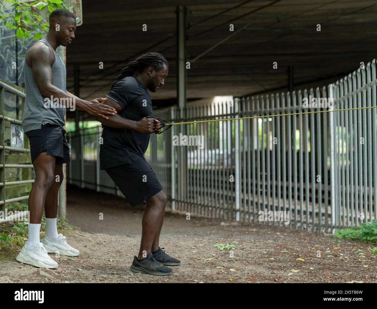 Two men doing strength training with resistance band outdoors Stock Photo